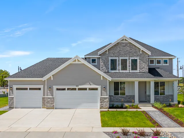 Contemporary home featuring a dual garage, stone and siding exterior, covered entry, and a paved walkway