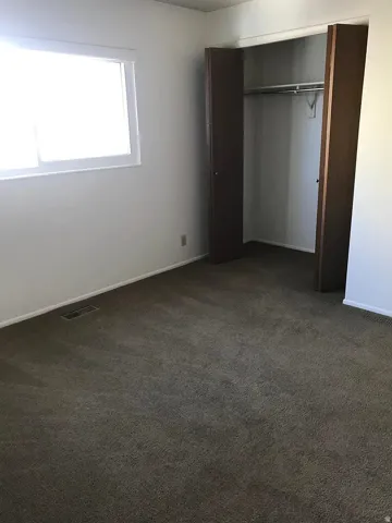 Carpeted room featuring a window and a closet with bifold doors