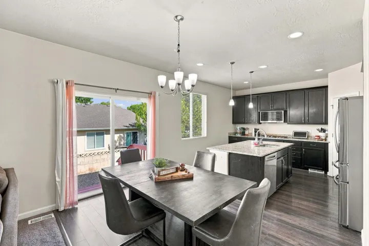Kitchen featuring dark wood-finish cabinetry, a central island with a sink, stainless steel appliances, and recessed lighting