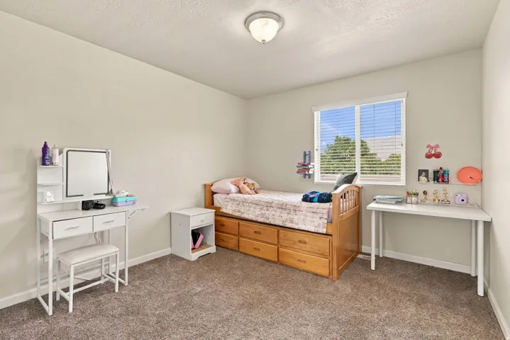 Neutral tone walls, carpet flooring, and a single window with blinds