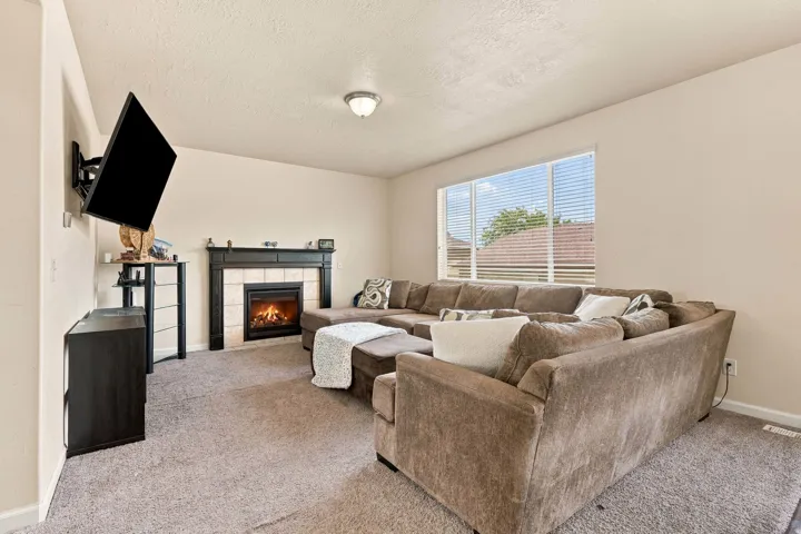 Carpeted living space with a built-in fireplace featuring a tiled surround and dark wood mantel