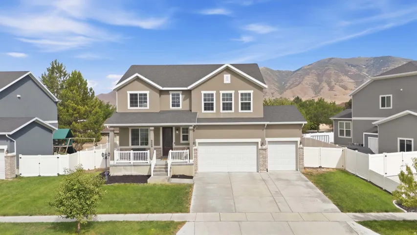 Two-story residence featuring a two-car garage with stone accents, a covered front porch, and a sidewalk leading to the front entry