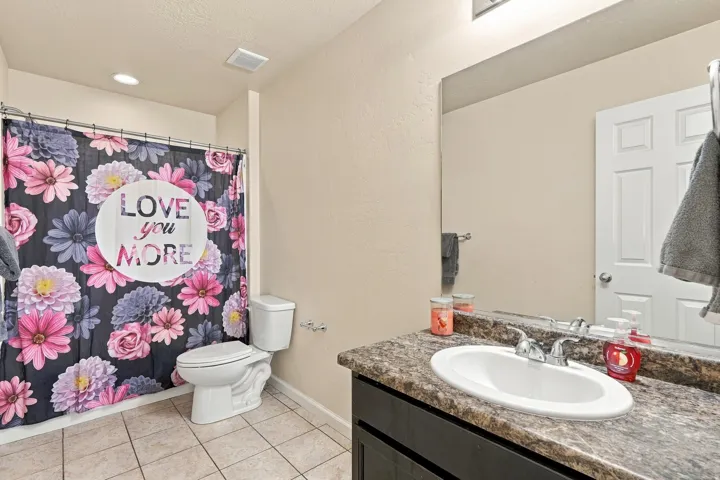 Bathroom featuring a vanity with a drop-in sink, chrome faucet, and a brown speckled countertop