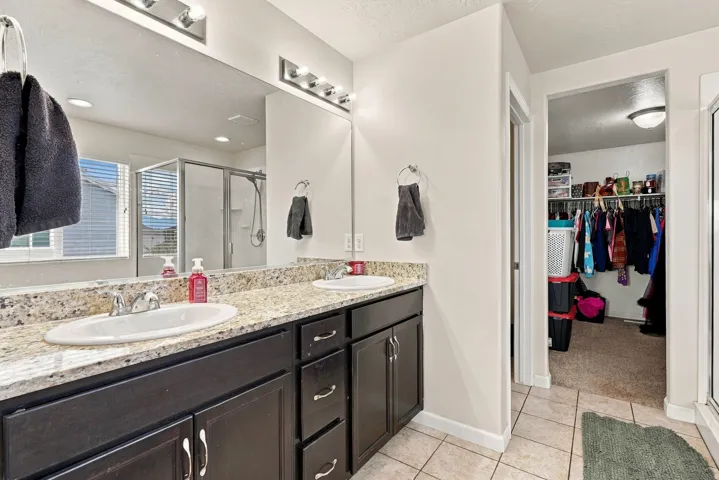 Dual vanity with stone countertop, dark wood-finish cabinetry, and individual rectangular sinks