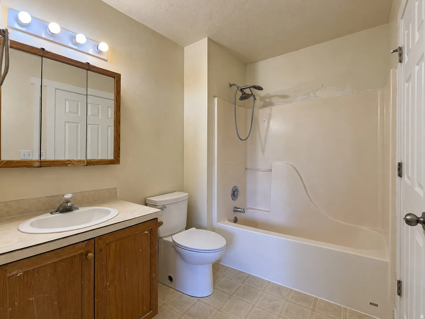 Bathroom featuring a single-sink vanity, built-in medicine cabinet, and a shower-tub combination