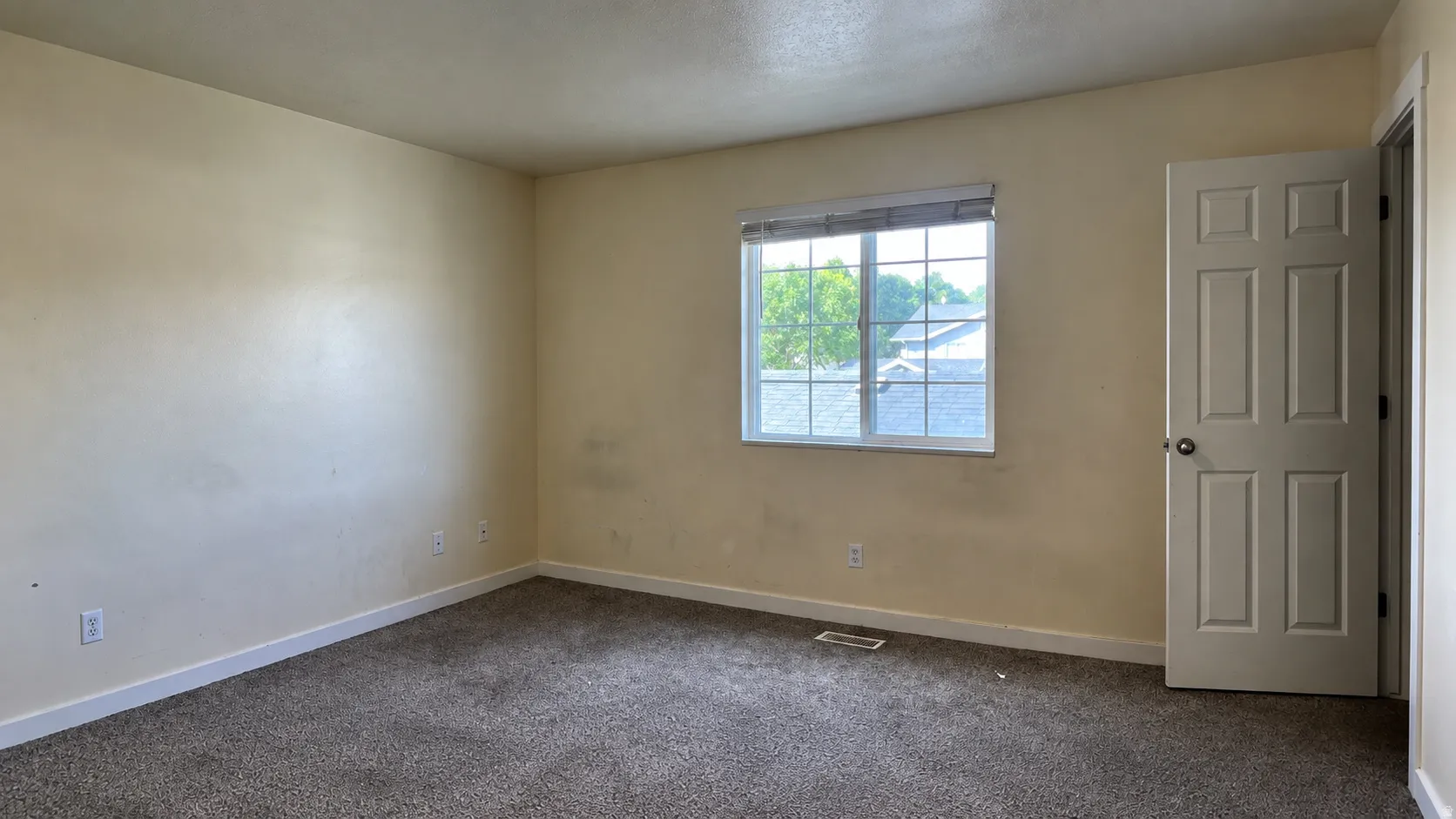 Carpeted room with a multi-pane window and a six-panel door