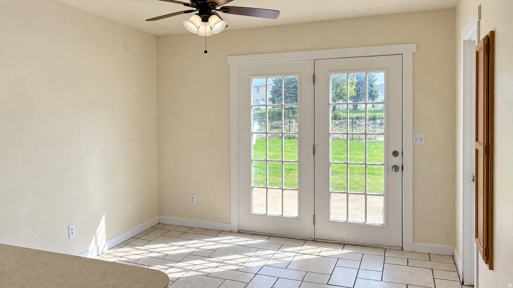 Dual French doors with glass panes, tile flooring, and a ceiling fan with integrated lighting