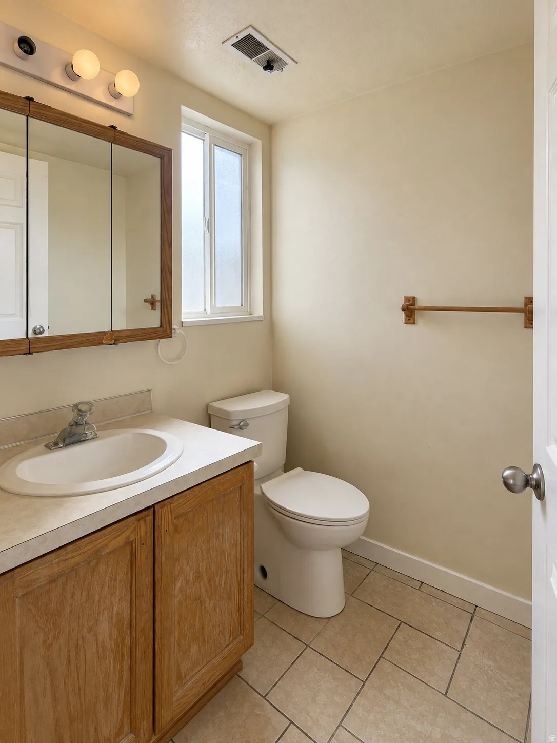 Built-in vanity with wood-finish cabinetry, integrated sink, and laminate countertop