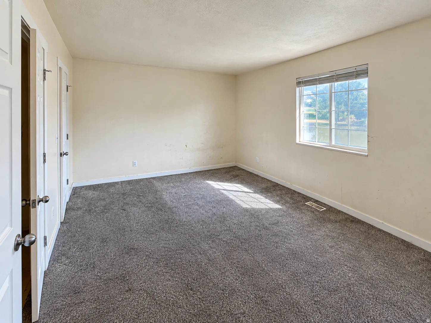 Neutral tone wall finishes, gray carpet flooring, white trim, and a window with blinds