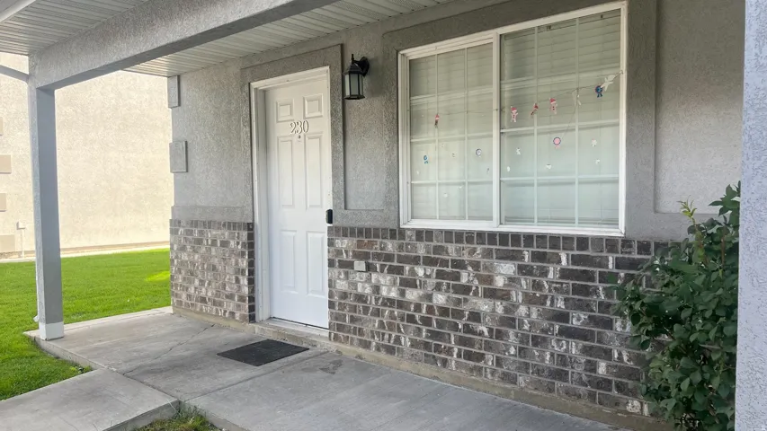 Exterior featuring a covered entry, brick facade, and a white paneled door