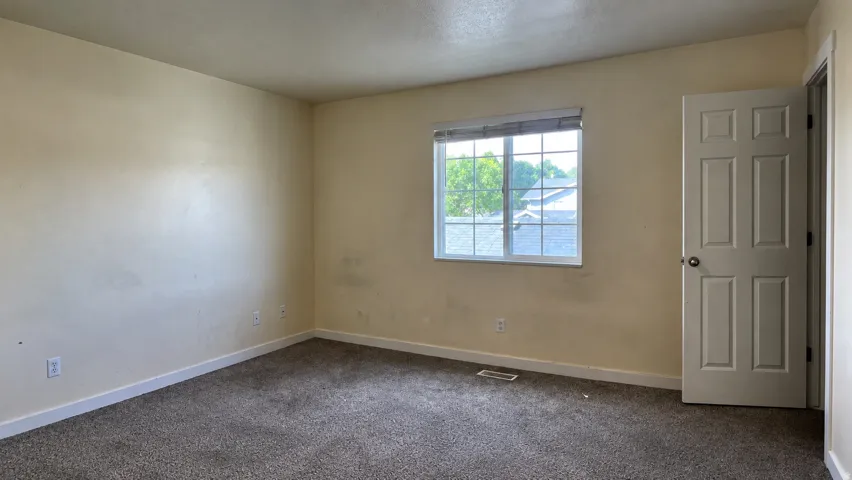 Carpeted room with a multi-pane window and a six-panel door