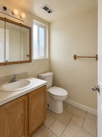 Built-in vanity with wood-finish cabinetry, integrated sink, and laminate countertop
