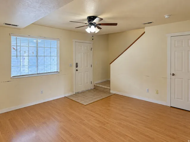 Wood-finish flooring, ceiling fan with light fixture, window with blinds, and white paneled interior doors