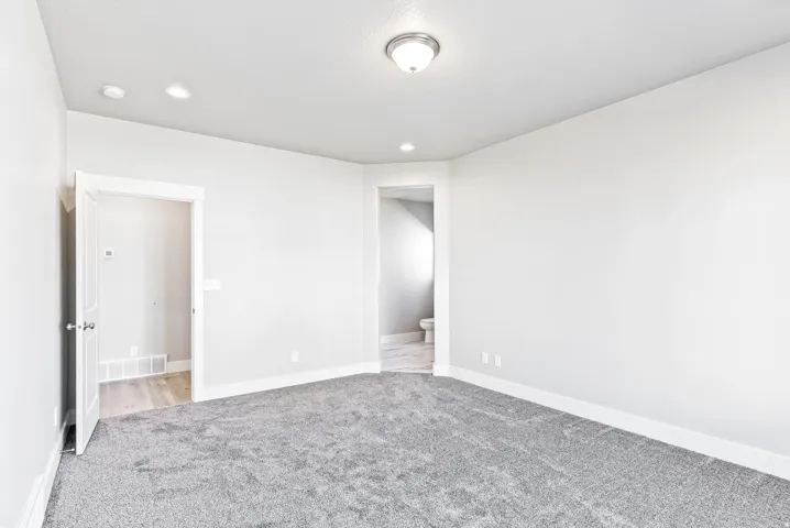 Plush gray carpeting, white painted walls, recessed ceiling lighting, and a semi-flush mount ceiling fixture