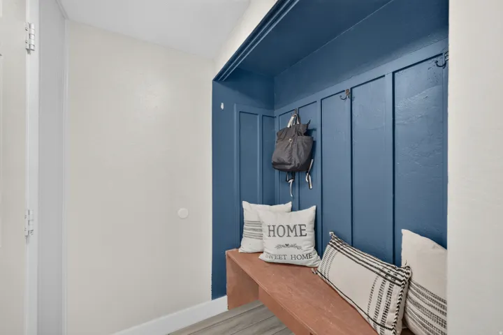 Built-in entryway bench with wood-finish top, board and batten wall paneling, and integrated coat hooks