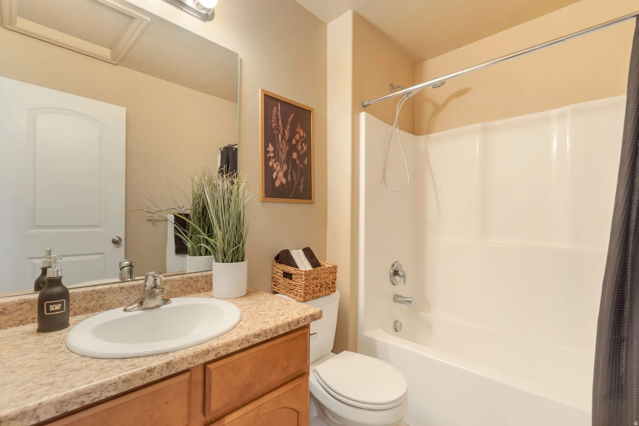 Vanity with an integrated sink, polished chrome faucet, wood-finish cabinetry, and a large wall-mounted mirror