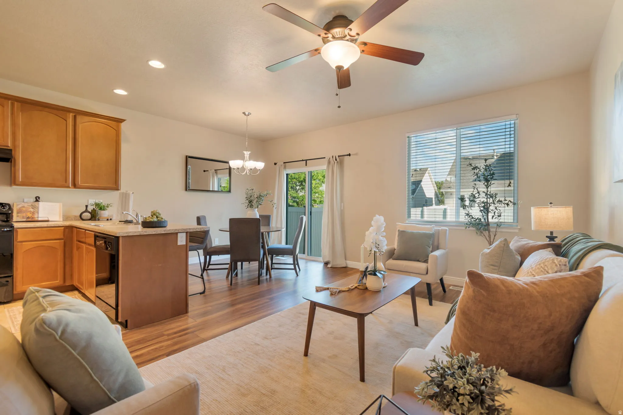 Open-concept living space with wood-finish flooring, a ceiling fan, recessed lighting, and a sliding glass door
