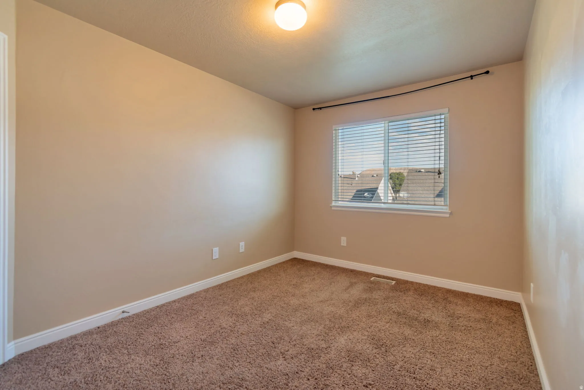 Bedroom with large closet.  Neutral tone walls with textured carpeting, a single window with horizontal blinds, and an overhead light fixture