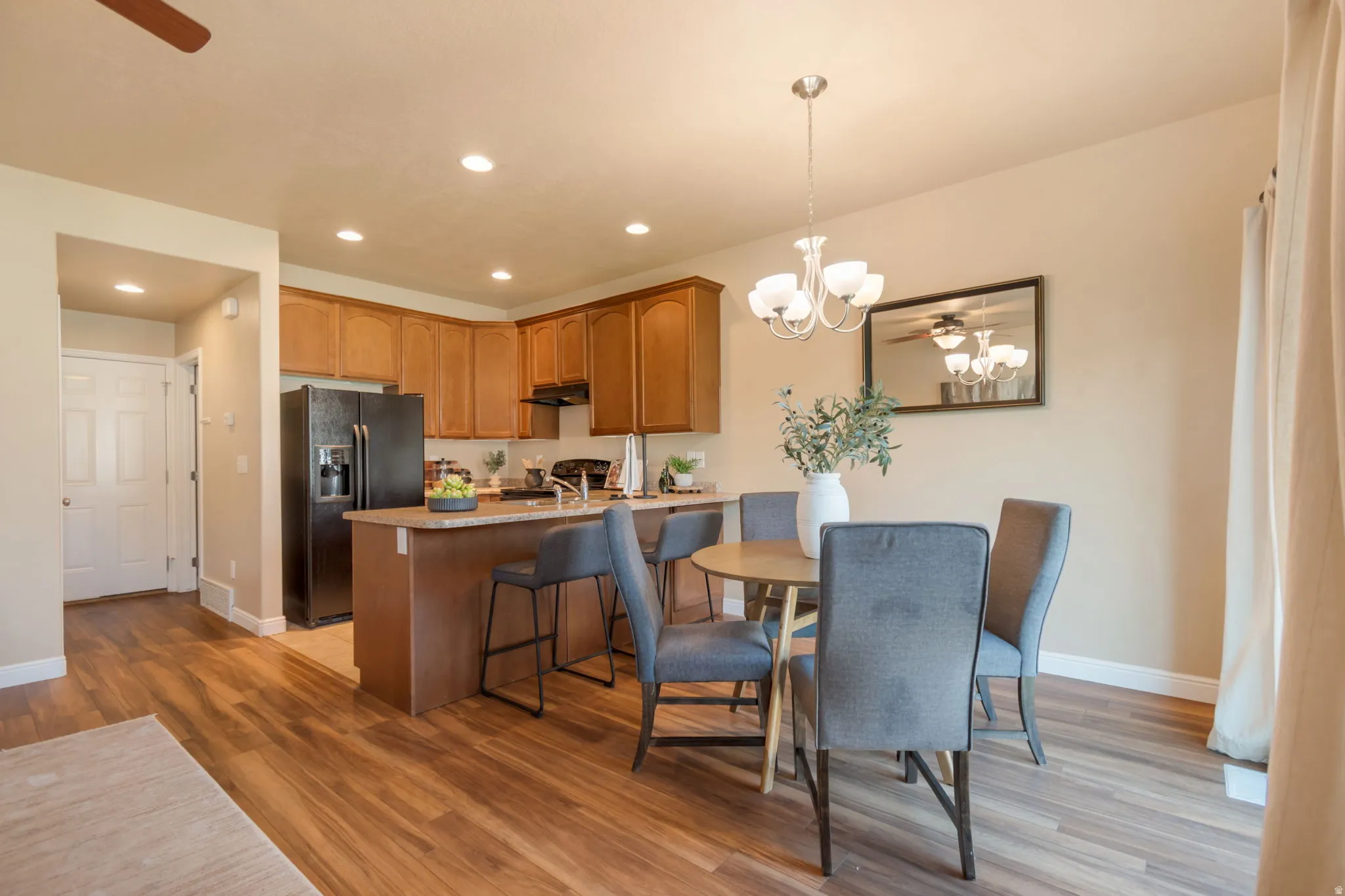 Wood-finish flooring throughout, recessed lighting, and a kitchen island with seating