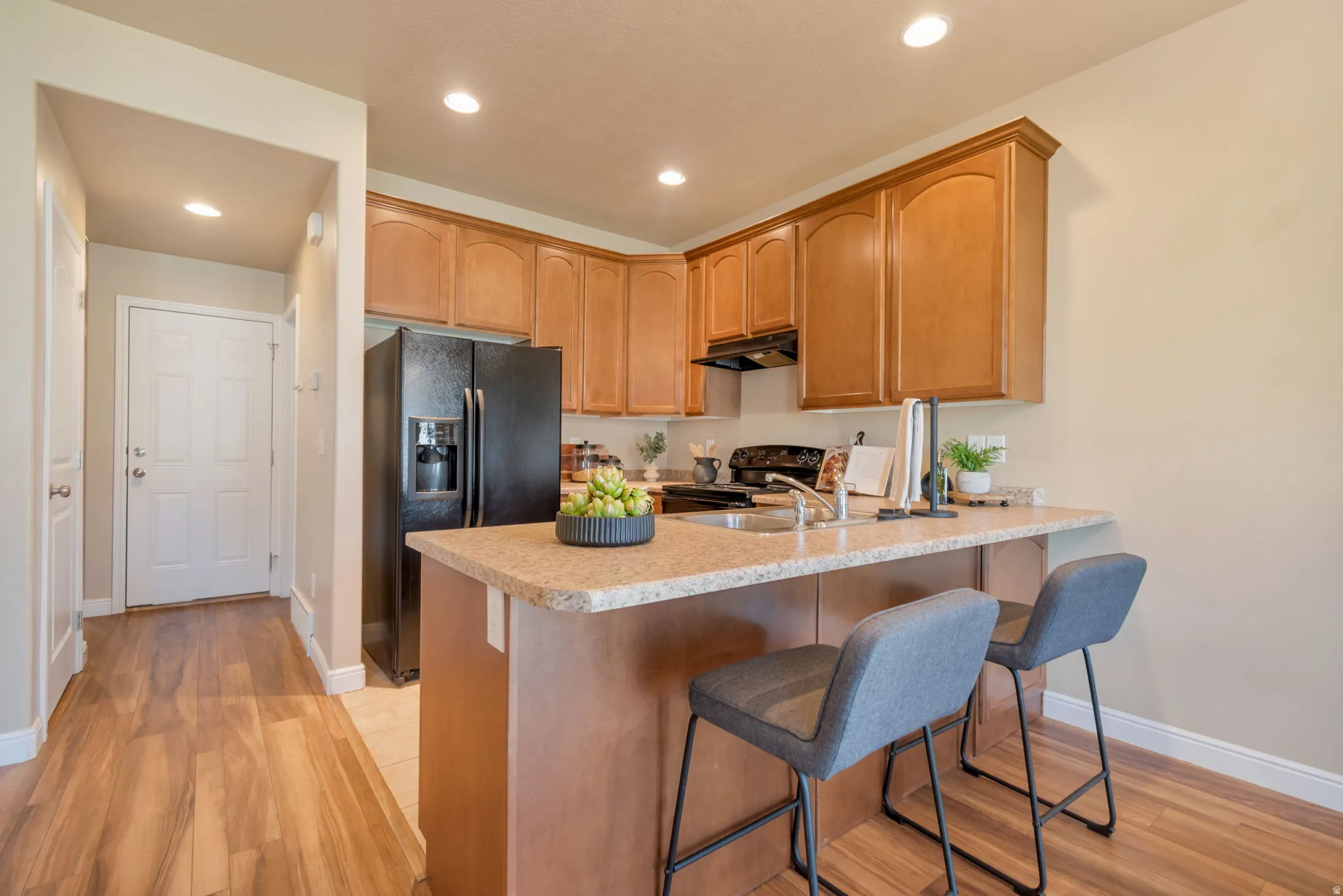 Kitchen featuring wood-finish cabinetry, granite-style countertops, stainless steel sink, and recessed lighting