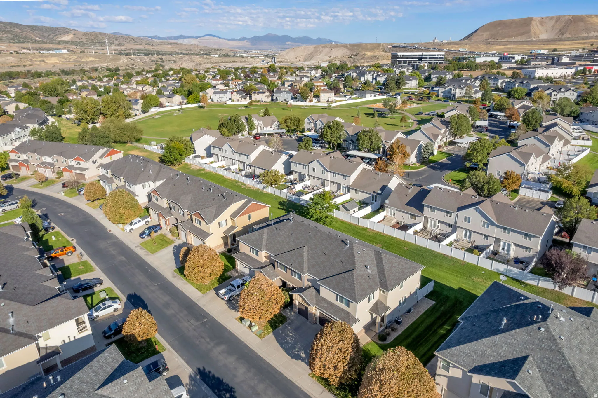 Residential neighborhood featuring rows of townhomes, paved streets, and a green space
