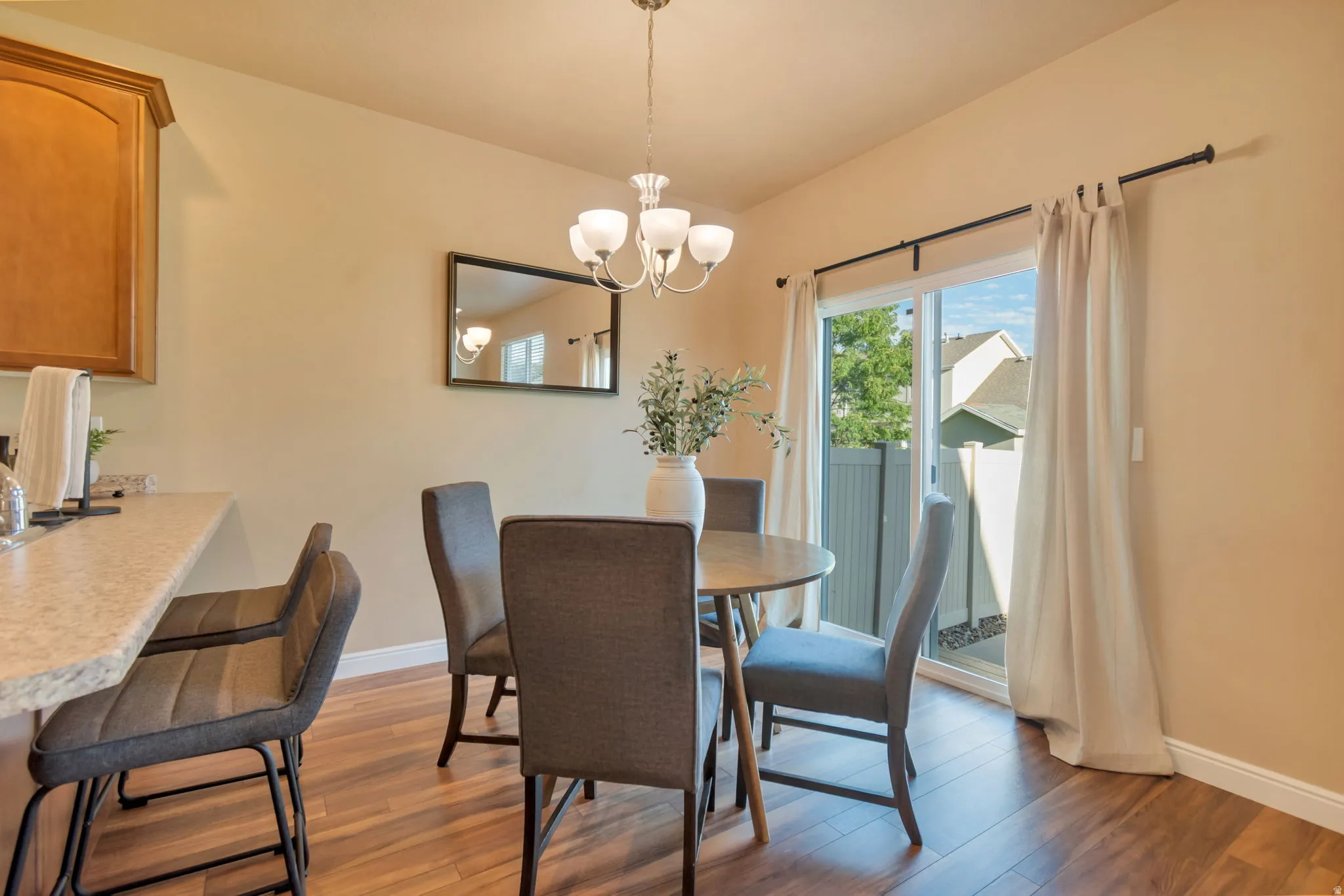 Wood-finish flooring, built-in cabinetry, sliding glass door, and a multi-light chandelier