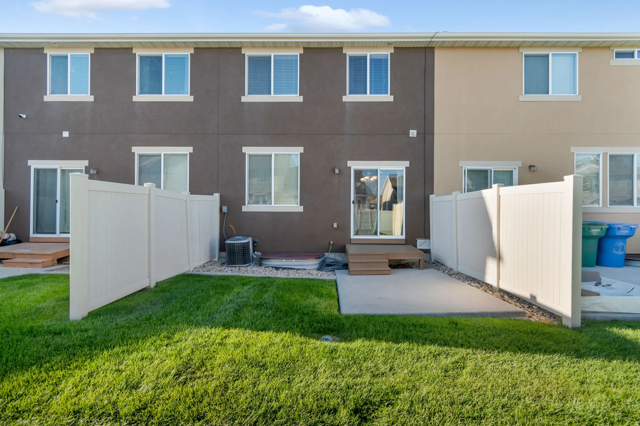 Private Patio at rear of building. Private fenced yard with a concrete patio, sliding glass door access, and a small wood-finish deck