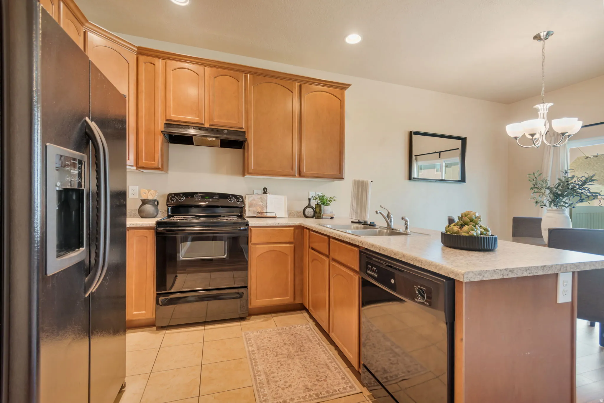 Kitchen featuring wood cabinetry, solid surface countertops, tile flooring, stainless steel appliances, and recessed lighting