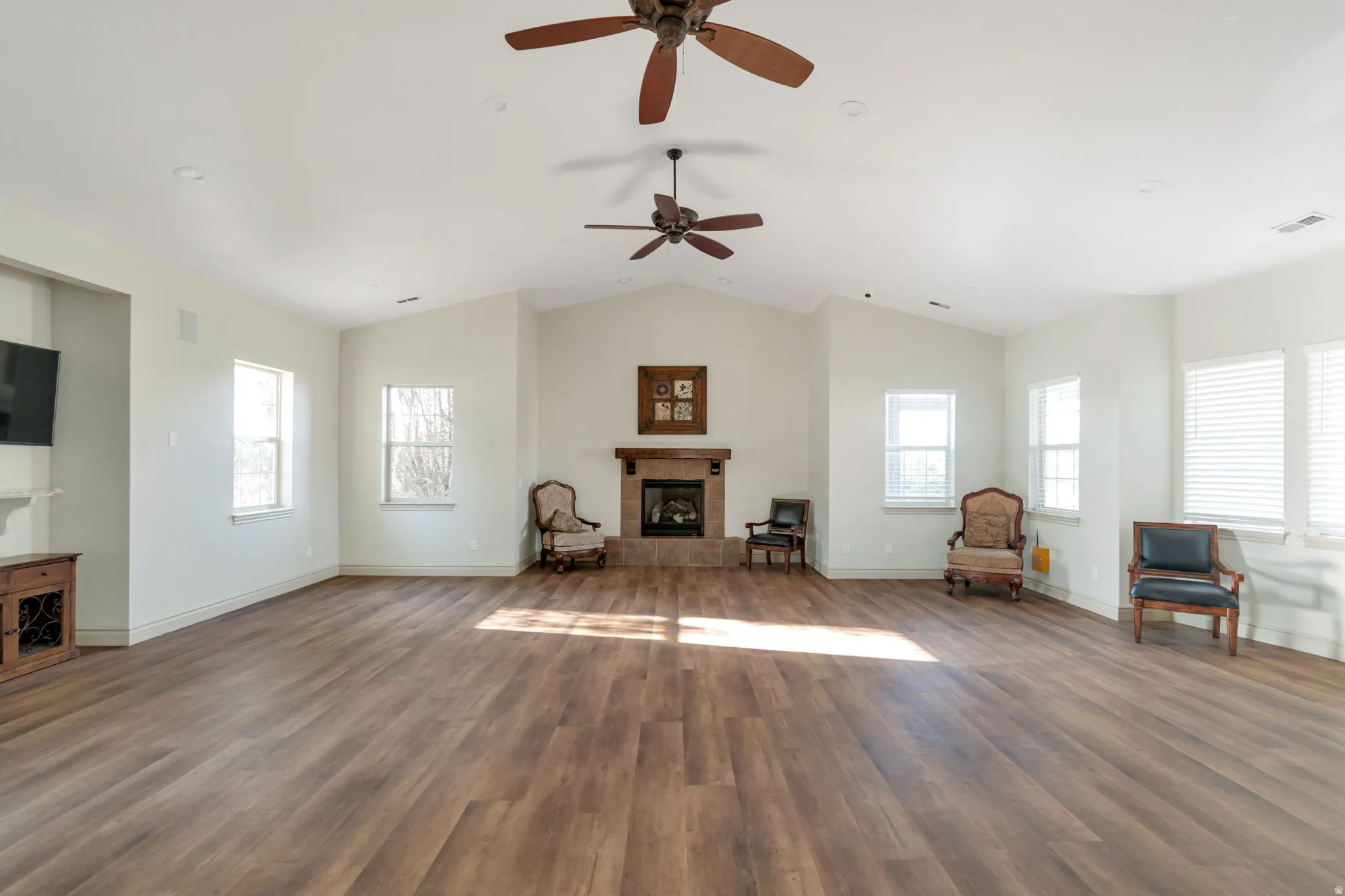 Club House spacious room with vaulted ceilings, wood-finish flooring, recessed lighting, and a fireplace with a stone surround