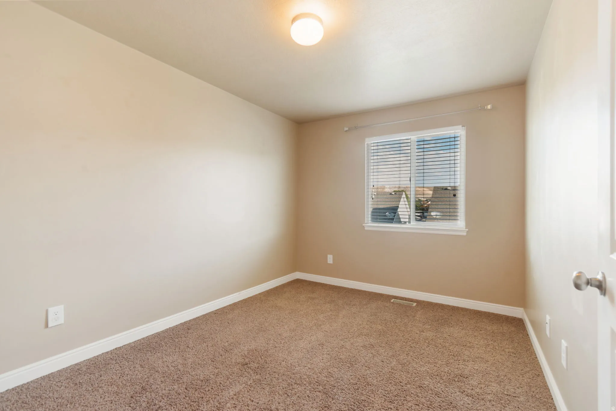 Nice bedroom with walk-in closet.  Carpeted interior with light beige painted walls, a flush-mount ceiling light fixture, and a single window with blinds