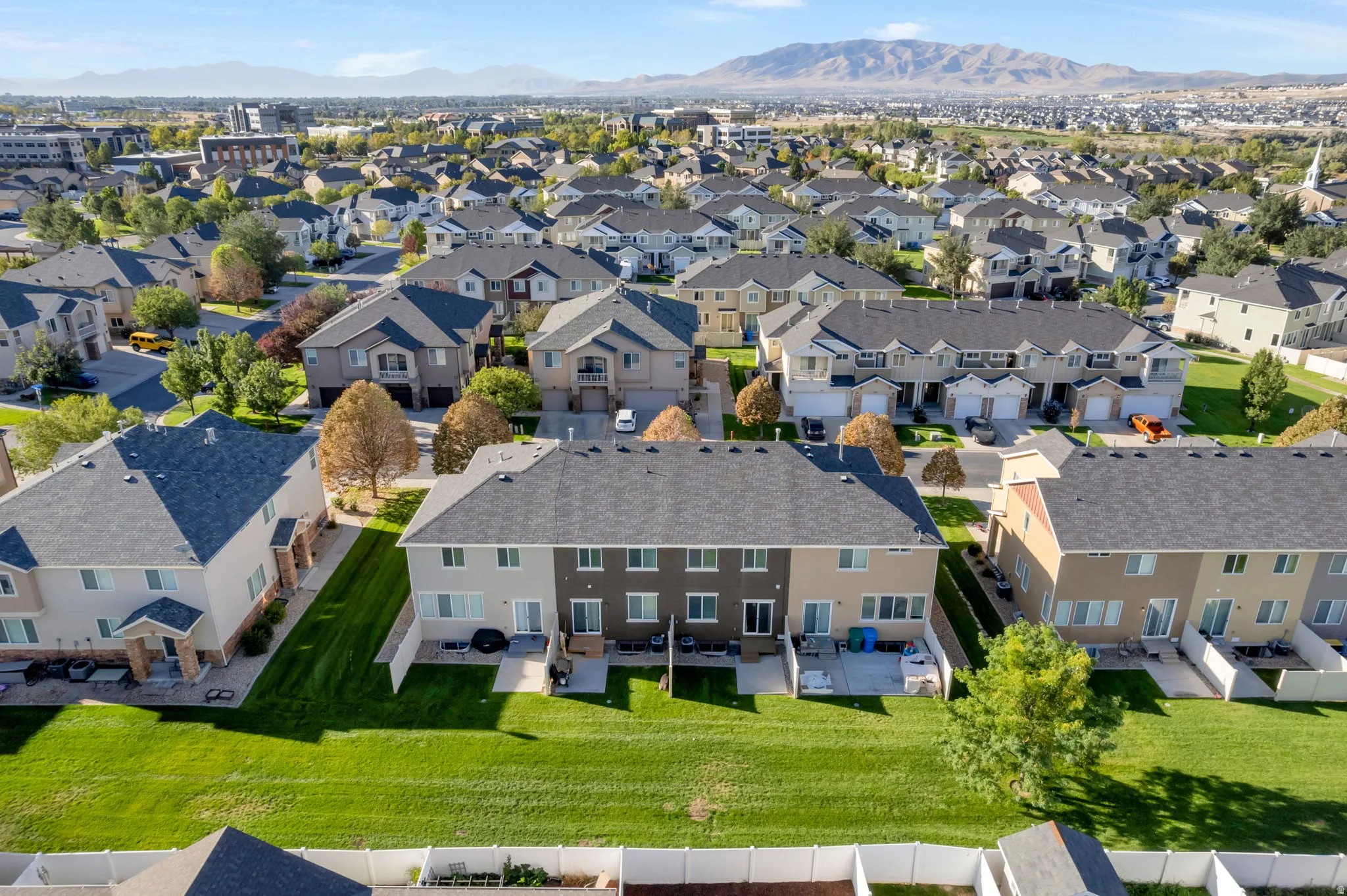 Residential development featuring multiple properties with dark shingle roofing, light-toned siding, and attached garages