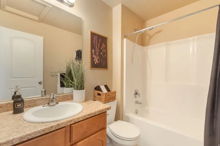 Vanity with an integrated sink, polished chrome faucet, wood-finish cabinetry, and a large wall-mounted mirror