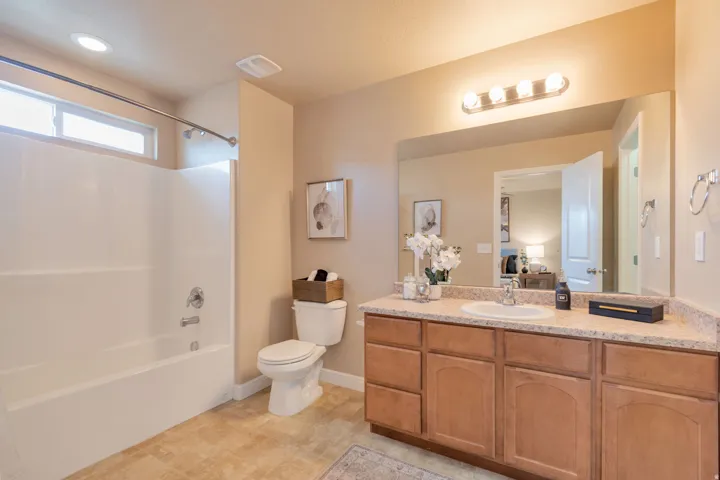 Primary bathroom off primary bedroom. Wood-finish vanity with a light-colored countertop and integrated sink