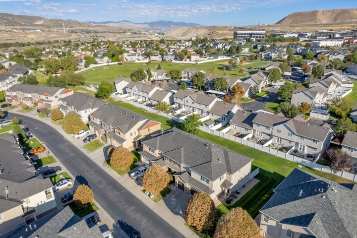 Residential neighborhood featuring rows of townhomes, paved streets, and a green space