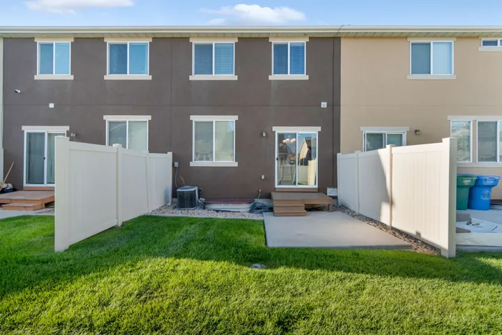 Private Patio at rear of building. Private fenced yard with a concrete patio, sliding glass door access, and a small wood-finish deck