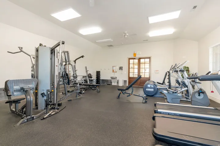 Fitness center featuring resilient rubber flooring, vaulted ceilings, and recessed lighting