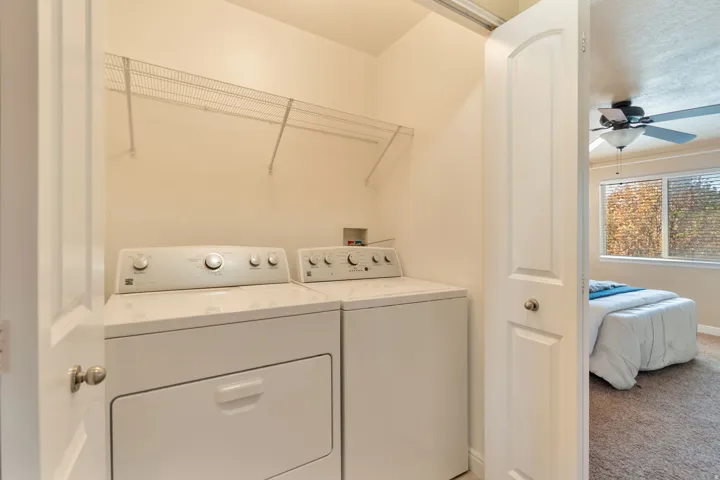 In hall right off bedrooms.  Laundry area with wire shelving, featuring a full-size washer and dryer
