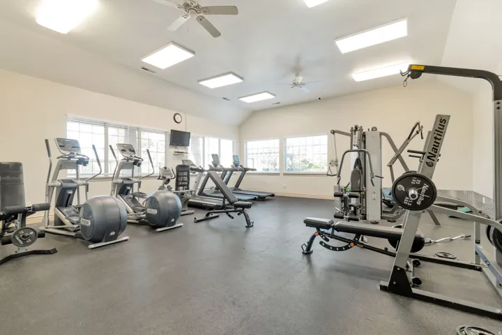 Fitness center featuring vaulted ceilings, ceiling fans, multiple windows, recessed lighting, and rubberized flooring