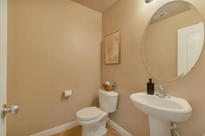 Pedestal sink with chrome faucet, oval wall mirror, and toilet