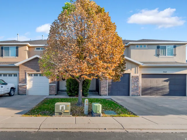 Stucco exterior with stone accents, attached garages, and mature landscaping