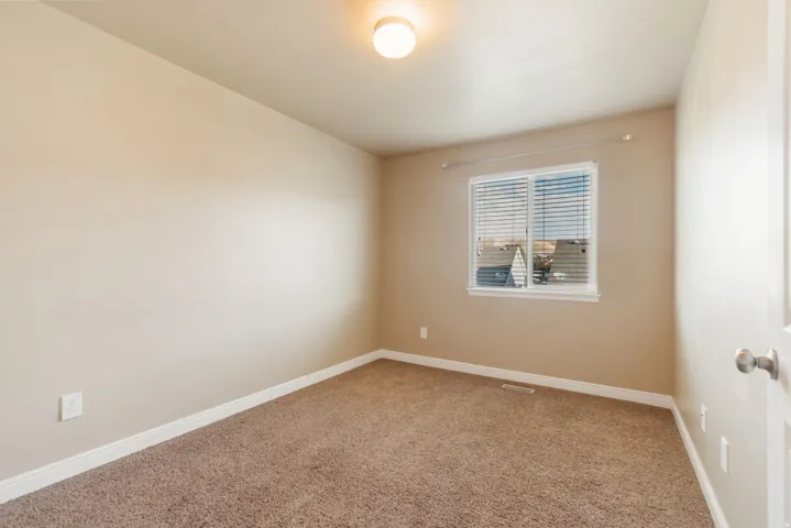 Nice bedroom with walk-in closet.  Carpeted interior with light beige painted walls, a flush-mount ceiling light fixture, and a single window with blinds