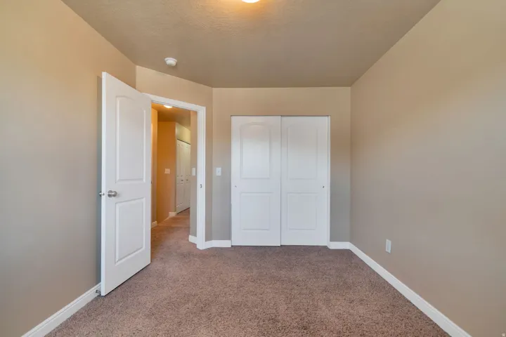 Neutral-toned walls, carpeted flooring, white trim, and a white bi-fold closet