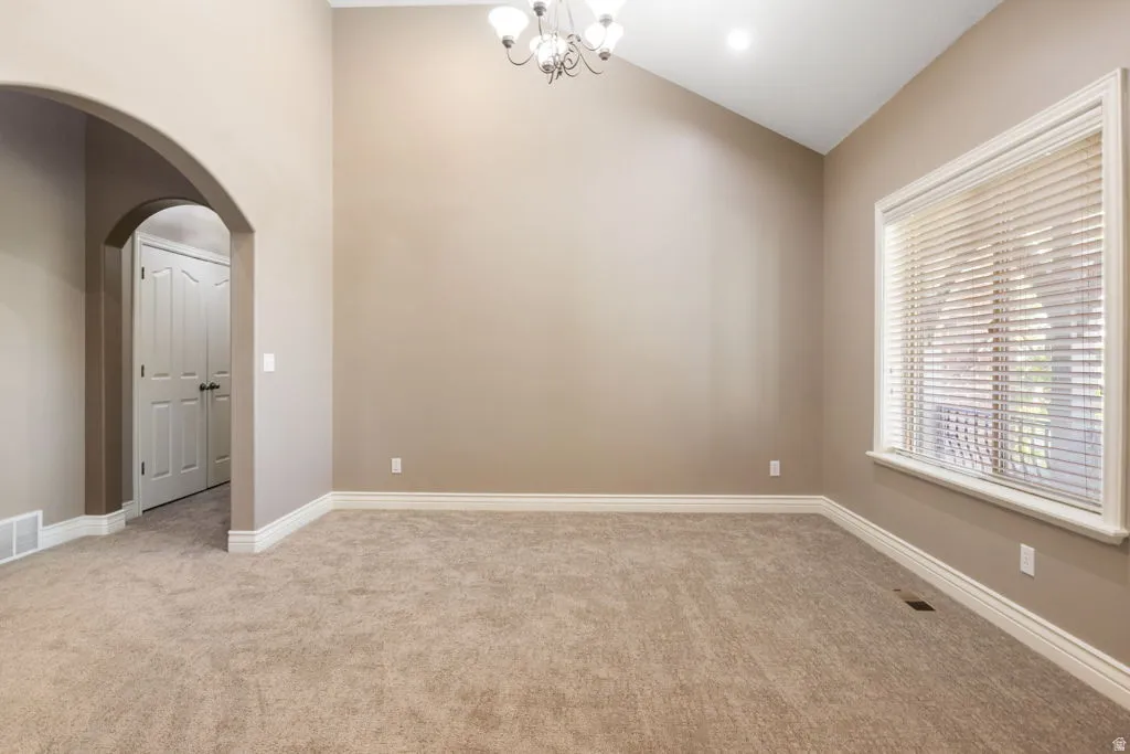 Vaulted ceiling with an arched doorway, recessed lighting, and a chandelier