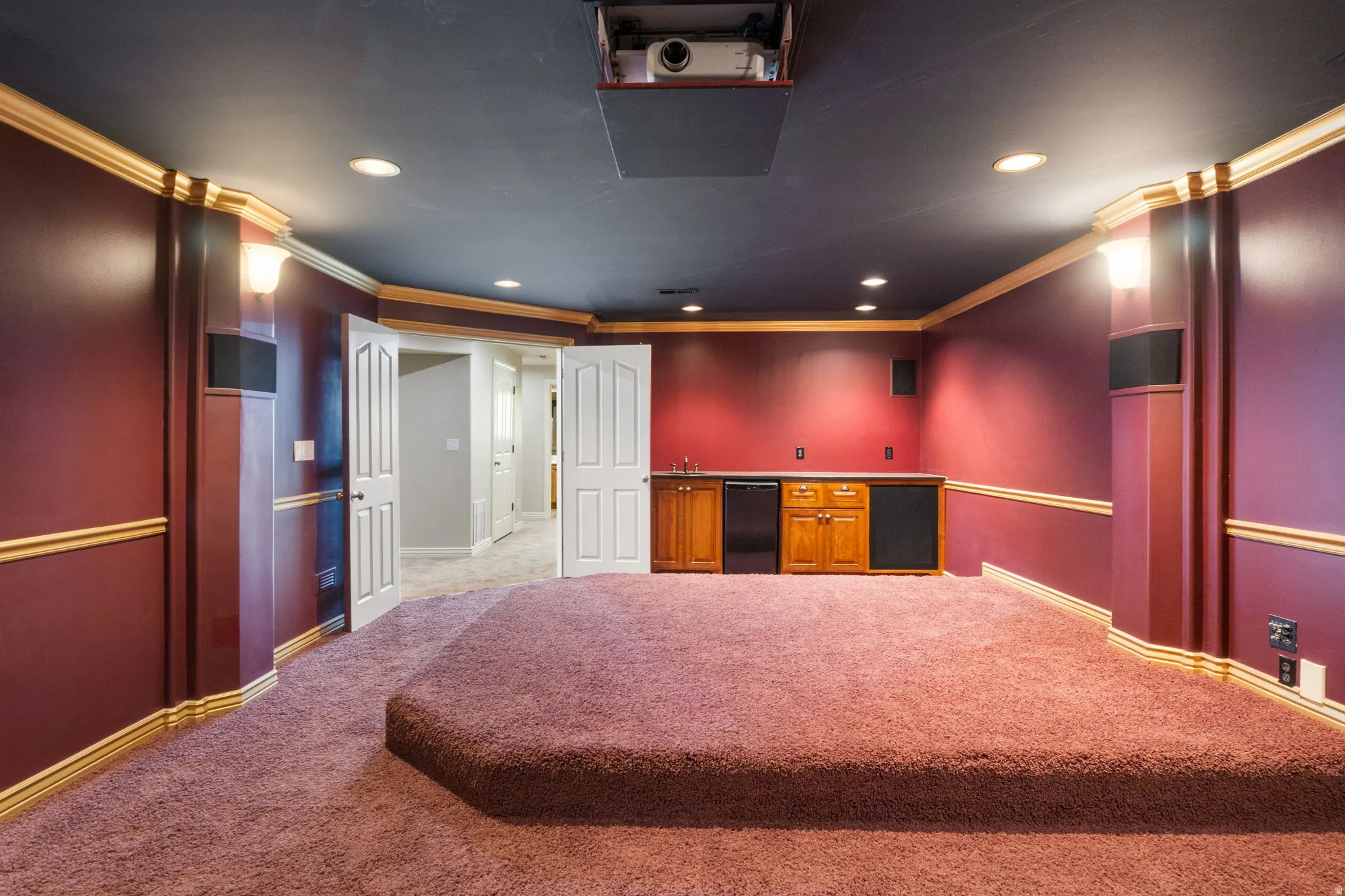 Built-in entertainment system with a projector, recessed lighting, and an integrated wet bar