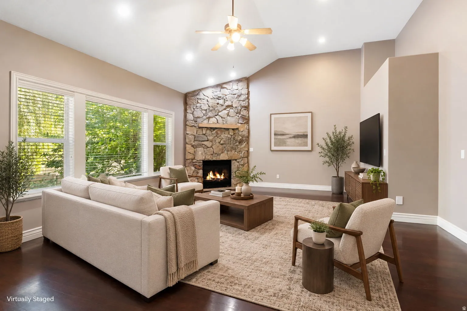 Vaulted ceiling with a ceiling fan, stone-faced fireplace, dark wood-finish flooring, recessed lighting, and large windows