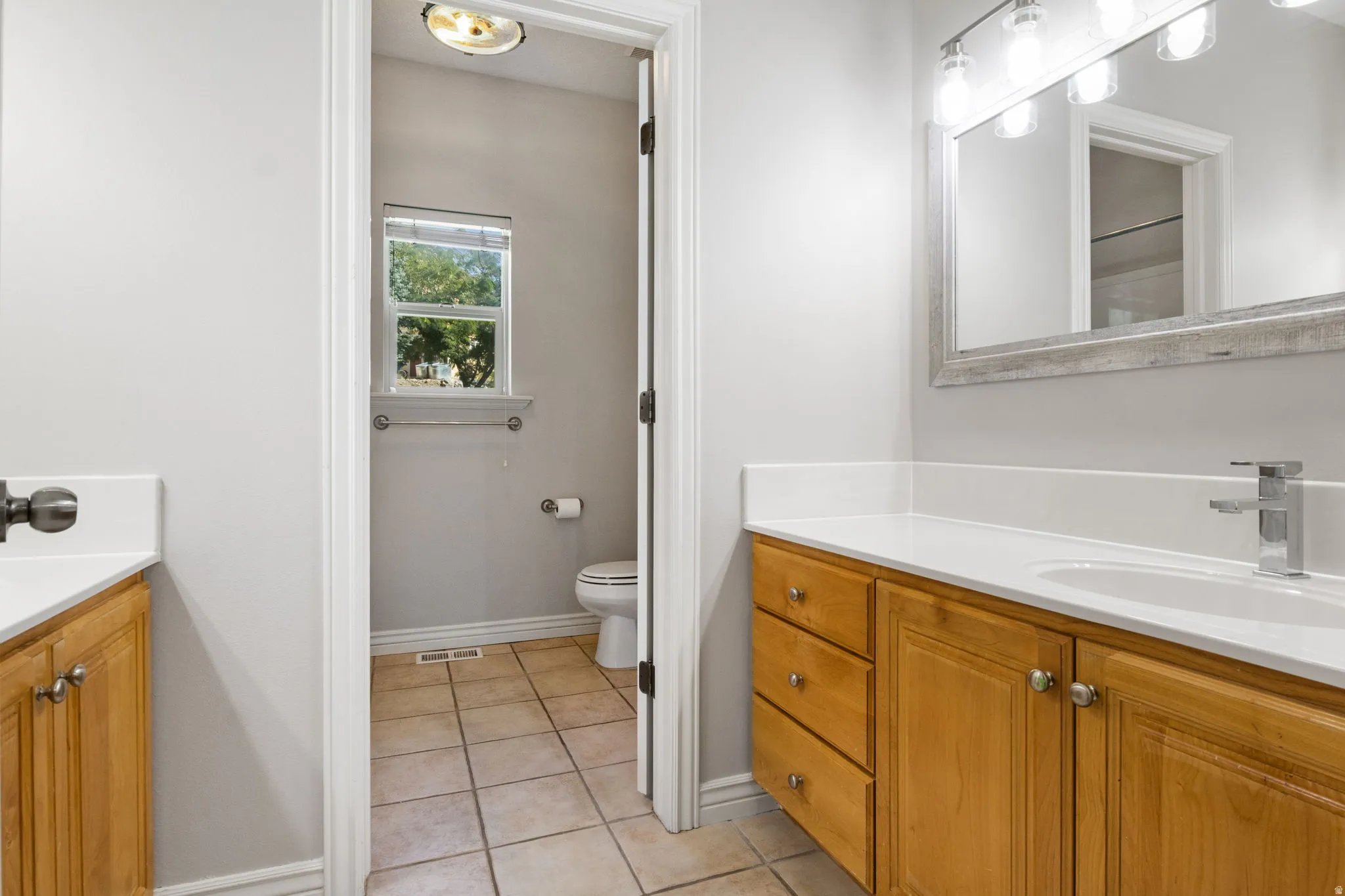 Dual vanity with light wood cabinetry, white countertops, and undermount sinks