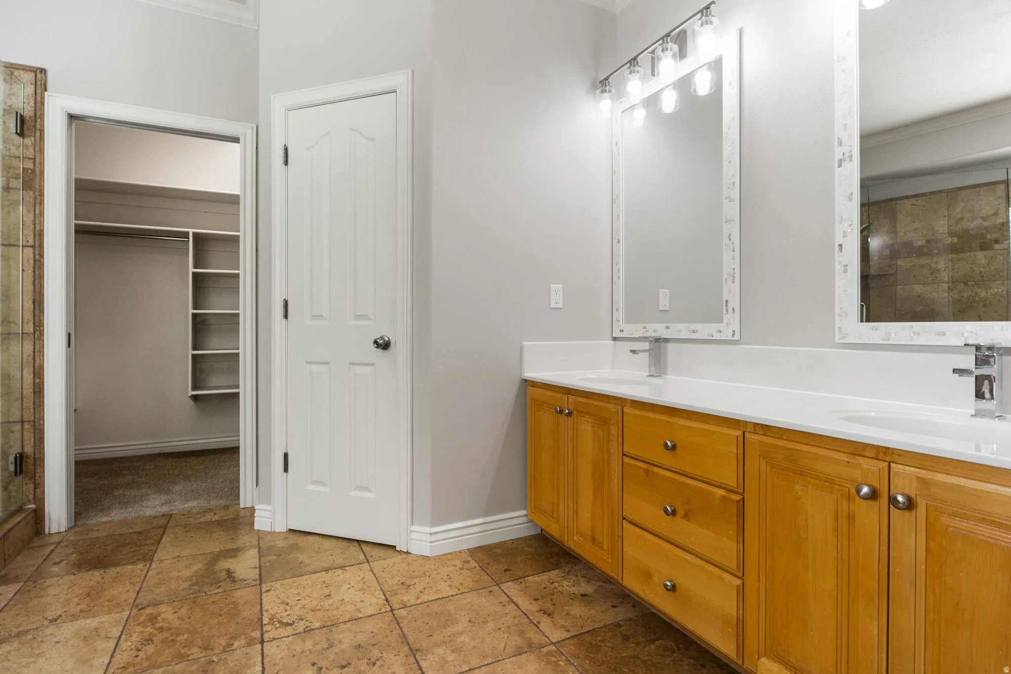 Dual vanity with white countertops, wood-finish cabinetry, and contemporary fixtures
