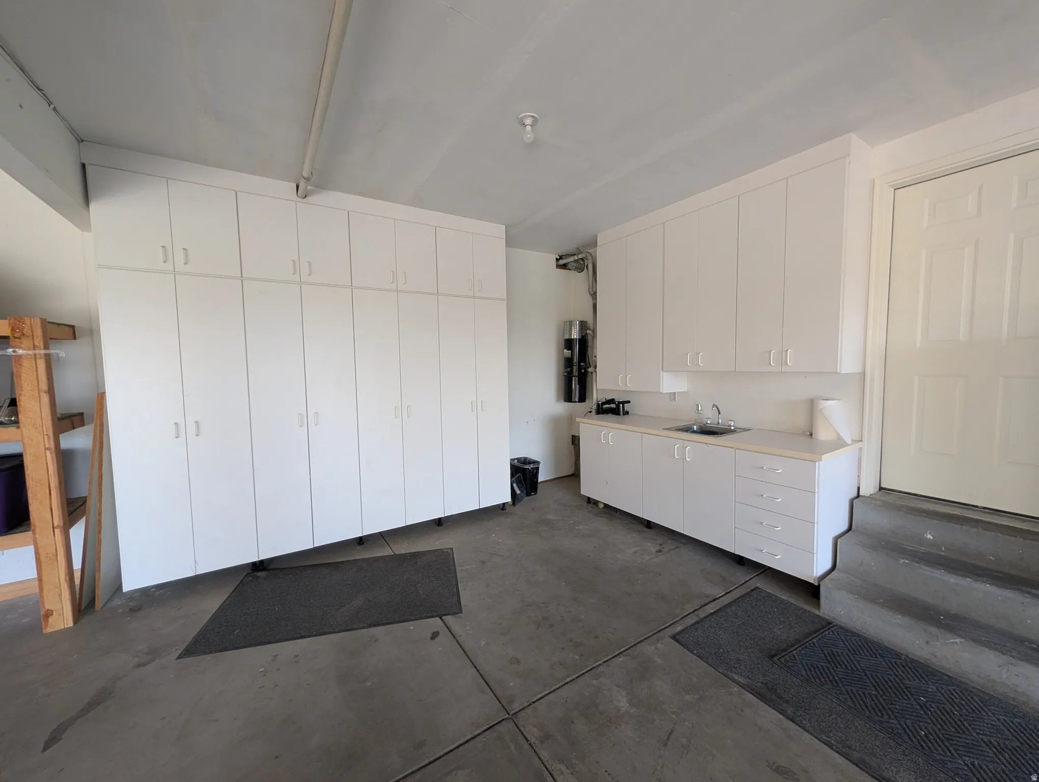 Built-in white cabinetry, integrated sink, and concrete flooring