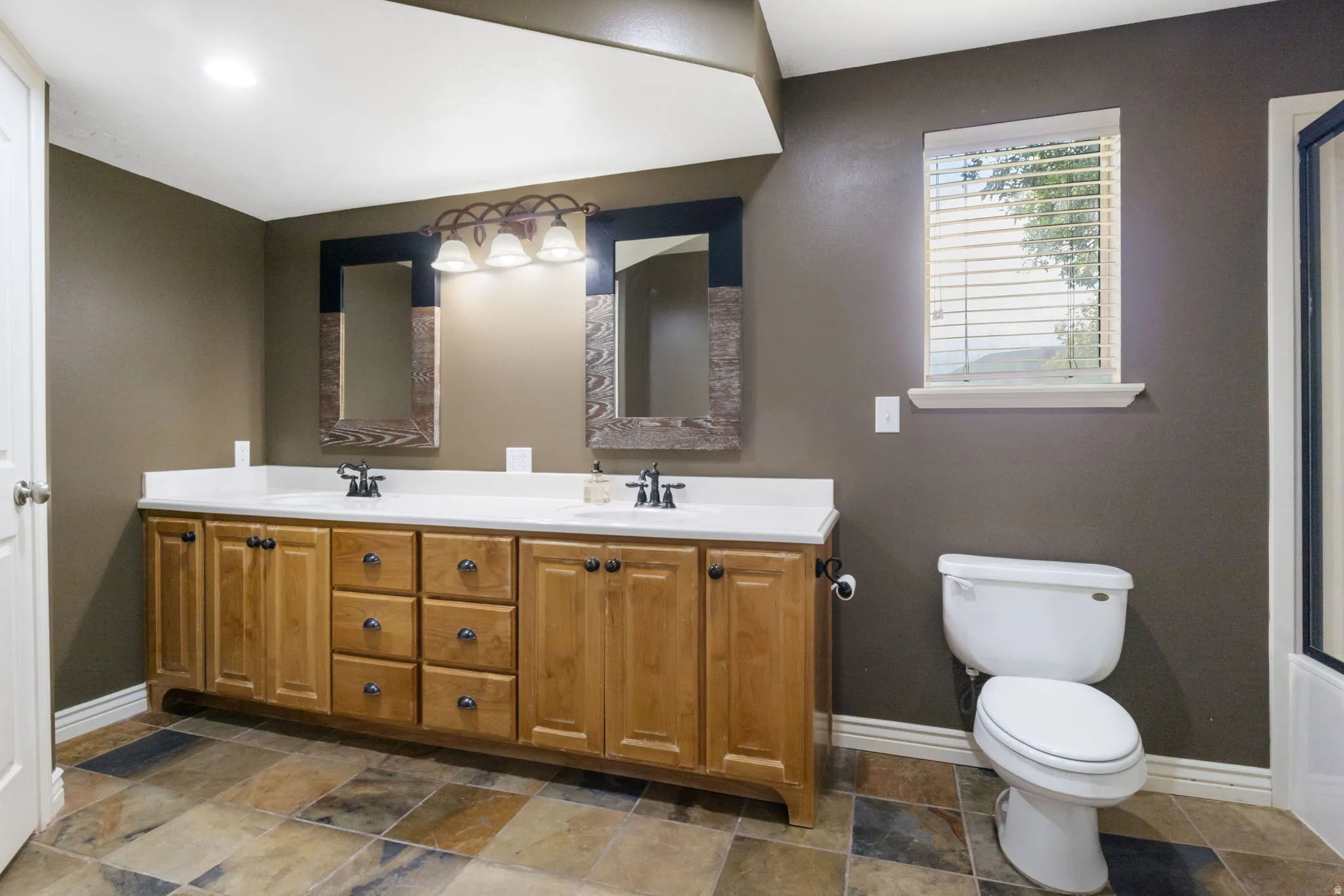 Double vanity with light wood cabinetry, dual sinks, and white countertops
