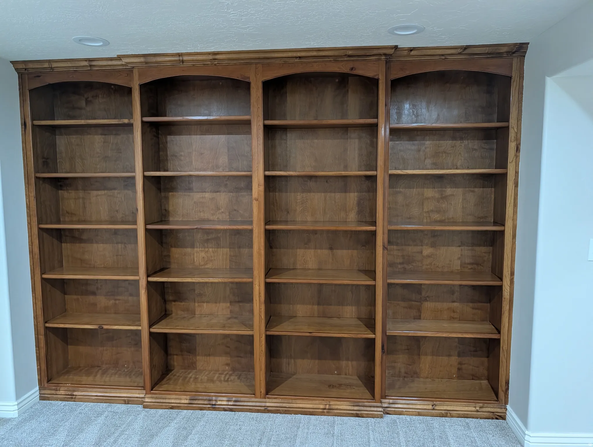Built-in wood shelving with arched tops and crown molding details